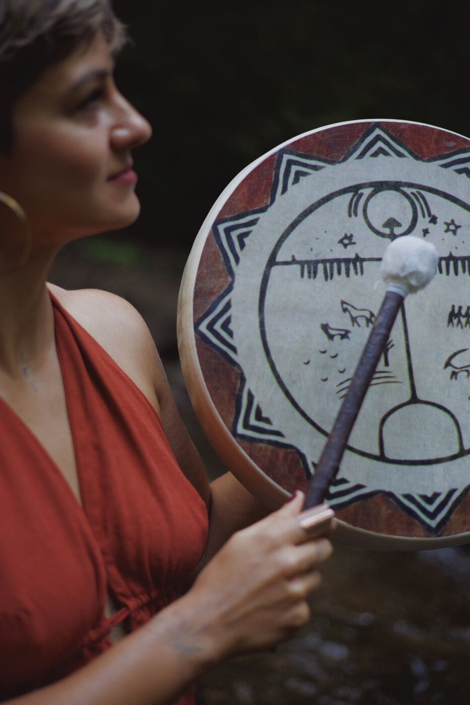 Neira holding a ceremonial drum in nature